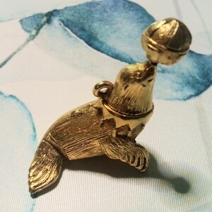 Vintage Max Factor circus seal solid perfume container pendant.  gold metal figurine compact with aquarius perfume