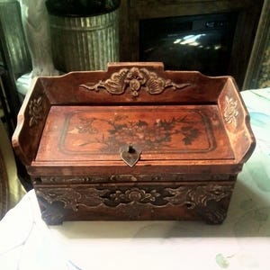 Joyero de madera oriental con diseño de pirograbado pintado a mano en color café y cajón secreto.