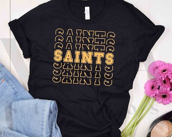May include: Black t-shirt with a graphic design of the word "Saints" repeated in a stacked pattern. The text is in a yellow color with a black outline.
