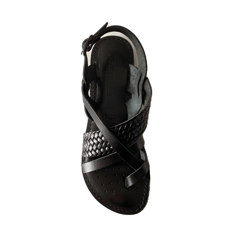 May include: Black leather sandals with a braided strap design. The sandals have a closed toe and an ankle strap.