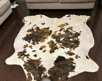 Puede incluir: Una alfombra de piel de vaca marrón, negra y blanca con una forma natural irregular. La alfombra mide aproximadamente 1,85 metros por 2,2 metros. LM24-049