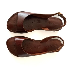 Puede incluir: Un par de sandalias de cuero marr&oacute;n con una correa de slingback. Las sandalias tienen un dise&ntilde;o simple y est&aacute;n hechas de cuero de alta calidad. El nombre de la marca "GRATTAROSE" est&aacute; impreso en la suela.