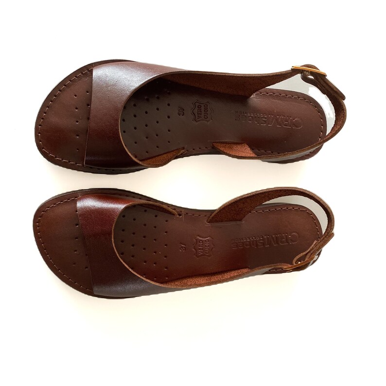 Puede incluir: Un par de sandalias de cuero marr&oacute;n con una correa de slingback. Las sandalias tienen un dise&ntilde;o simple y est&aacute;n hechas de cuero de alta calidad. El nombre de la marca "GRATTAROSE" est&aacute; impreso en la suela.