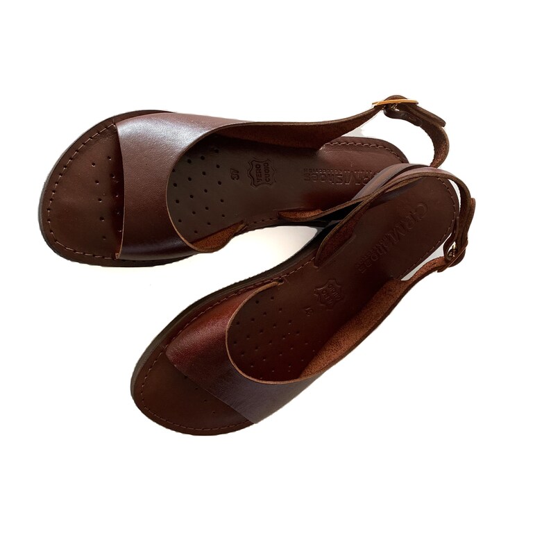 Puede incluir: Un par de sandalias de cuero marr&oacute;n con una correa de slingback. Las sandalias tienen un dise&ntilde;o simple y est&aacute;n hechas de cuero de alta calidad.