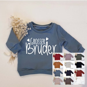 Könnte beinhalten: Ein blaues Sweatshirt mit dem Text "Grosser Bruder" in Weiß. Das Sweatshirt ist in verschiedenen Farben erhältlich, darunter Rot, Nude, Khaki, Karamell, Creme, Schwarz, Petrol, Marine, Terrakotta, Rose, Taupe und Creme.