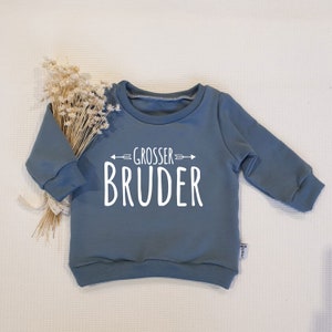 Könnte beinhalten: Ein blauer Baby-Sweatshirt mit weißem Text, der "grosser bruder" mit Pfeilen auf beiden Seiten des Wortes "grosser" lautet.