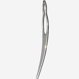 May include: A silver-colored latch hook tool, designed for hair braiding or rug hooking. The tool has a curved, elongated shape with a small eyelet at the top and a hook at the bottom. The tool is made of metal and has a smooth, polished finish.