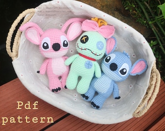 May include: Three crocheted stuffed toys in a wicker basket. The toys are pink, green, and blue and are inspired by the characters from the Disney movie Lilo & Stitch. The pink toy has large black eyes and a black nose. The green toy has a single black eye, a red mouth, and a red button nose. The blue toy has two black eyes and a black nose. The basket is lined with white fabric with a floral pattern.
