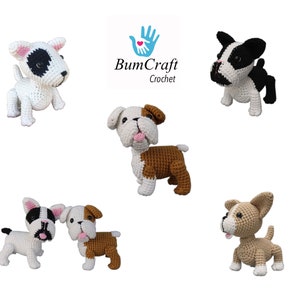 May include: Five crocheted dog toys in various poses. The dogs are white, black, brown, and tan with black eyes and pink noses. The dogs are all smiling. The image includes the text "BumCraft Crochet".