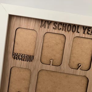 May include: A white-framed wooden display board with the laser-cut text MY SCHOOL YEARS at the top. The board features multiple rectangular cutouts for photographs, with the labels RECEPTION, 1, and 2 engraved below specific openings.
