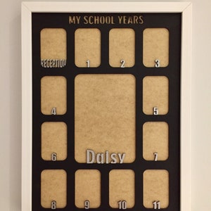 May include: A white-framed collage photo frame with a black mat board featuring the text MY SCHOOL YEARS at the top. It includes twelve small rectangular openings labeled Reception through 11, and one large central opening labeled Daisy.