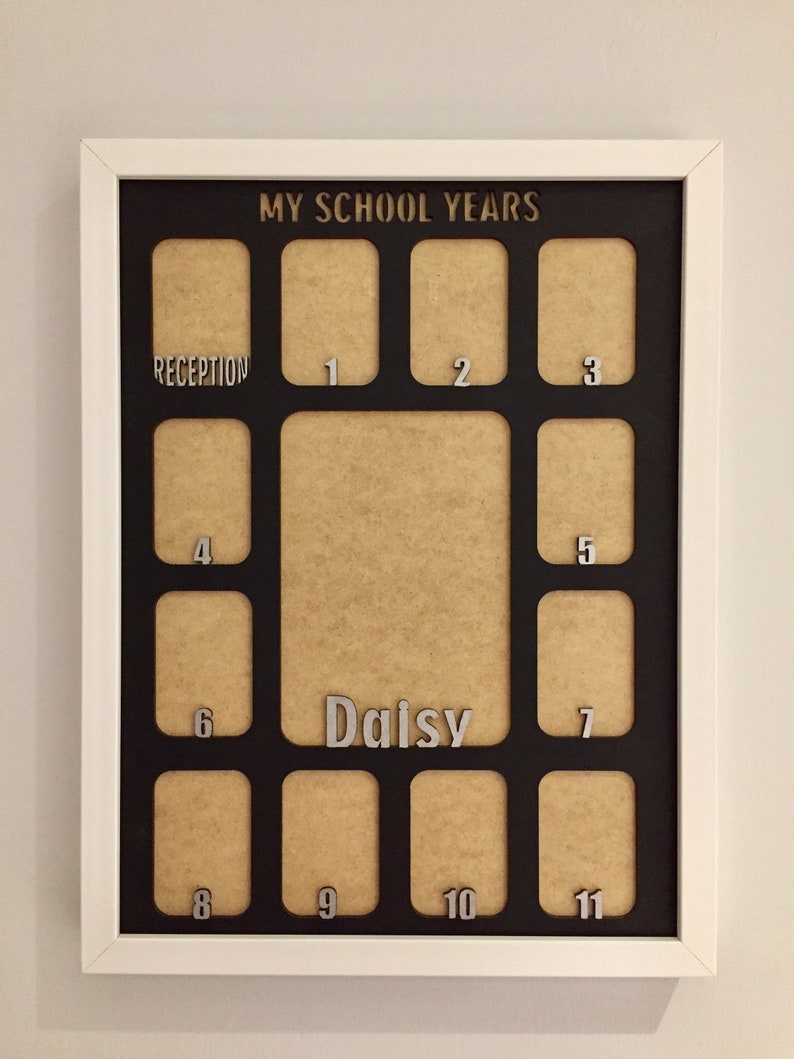 May include: A white-framed collage photo frame with a black mat board featuring the text MY SCHOOL YEARS at the top. It includes twelve small rectangular openings labeled Reception through 11, and one large central opening labeled Daisy.