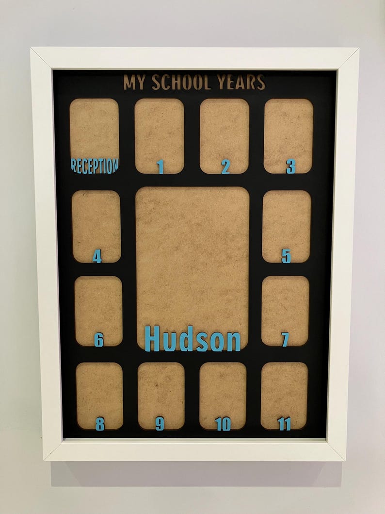 May include: A white rectangular picture frame with a black mat featuring the text MY SCHOOL YEARS at the top and the name Hudson in the center. It contains twelve small photo slots labeled Reception through 11 in light blue lettering.