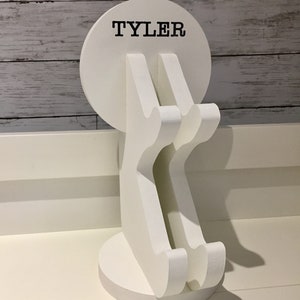 K&ouml;nnte beinhalten: Wei&szlig;er Telefonst&auml;nder aus Holz mit runder Basis und zwei geschwungenen Armen. Der St&auml;nder tr&auml;gt den Namen "TYLER" auf der Vorderseite.