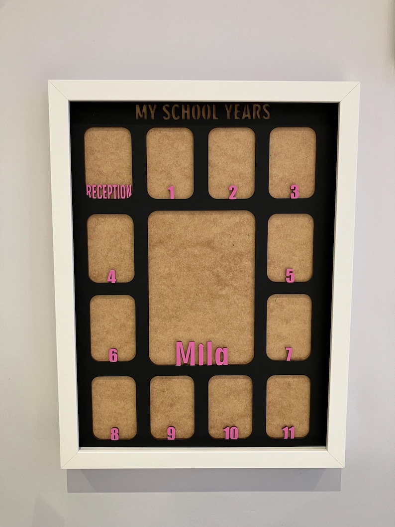 May include: A white framed collage picture board titled MY SCHOOL YEARS in gold lettering. It features a black background with twelve small rectangular photo slots and one large central slot. Pink labels mark Reception through year 11, with the name Mila in pink.