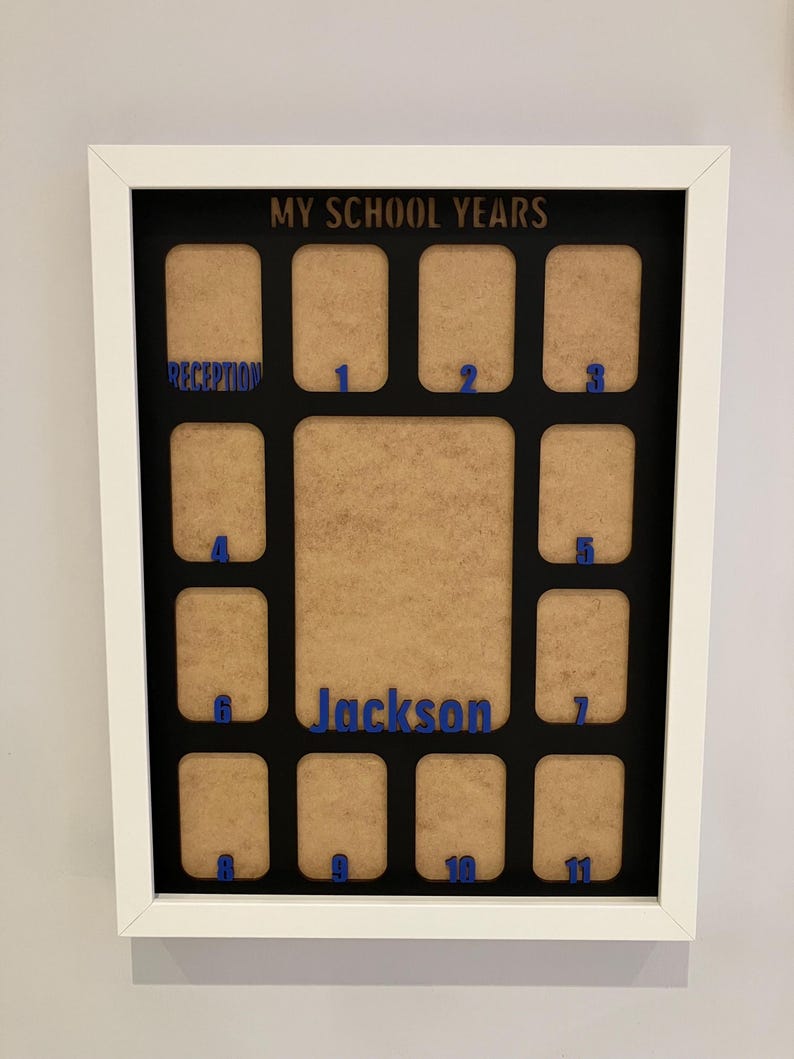 May include: A white rectangular picture frame with a black mat board featuring the text MY SCHOOL YEARS at the top. It contains twelve small photo slots labeled Reception through 11 in blue, plus a larger central slot labeled Jackson in blue.