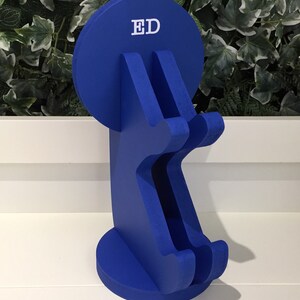 K&ouml;nnte beinhalten: Ein blauer, h&ouml;lzerner Telefonst&auml;nder mit einer runden Oberseite, auf der "ED" in wei&szlig;en Buchstaben steht. Der St&auml;nder hat zwei F&auml;cher f&uuml;r Telefone.