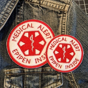 May include: Two red and white medical alert patches with the text "MEDICAL ALERT EPIPEN INSIDE" on a blue denim jacket.