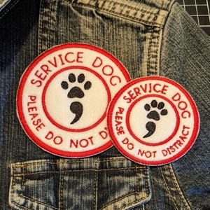 May include: Two red and white service dog patches with paw prints and the text "Service Dog Please Do Not Distract" on a blue denim jacket.