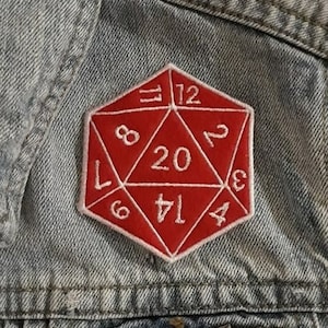 May include: A red twenty-sided die patch with white numbers sewn onto a denim jacket.
