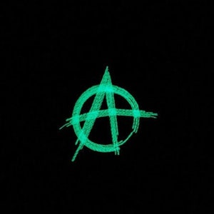 May include: A green anarchy symbol drawn in a circle on a black background.