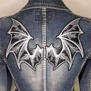 Peut inclure: Deux patchs thermocollants en forme d'ailes de chauve-souris brodées en noir et blanc. Les ailes sont ornées de motifs complexes et sont parfaites pour ajouter une touche gothique aux vêtements ou aux accessoires.