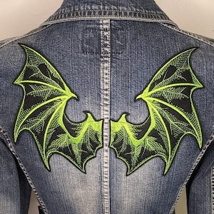 May include: A denim jacket with a green and black embroidered dragon wing patch on the back.