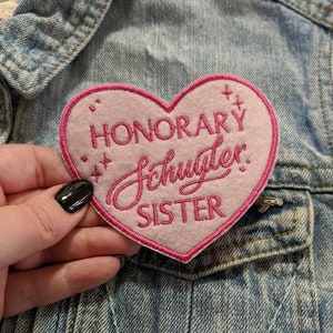 May include: Pink heart-shaped patch with the text "HONORARY SCHUYLER SISTER" in pink lettering.