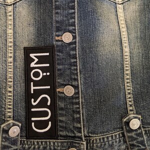 May include: A denim jacket with a black patch that says "CUSTOM" in white lettering.