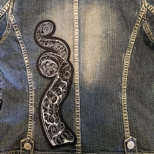 May include: A black denim jacket with a white embroidered octopus patch on the back.