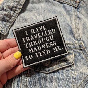 May include: Black embroidered patch with white text that reads "I have travelled through madness to find me."