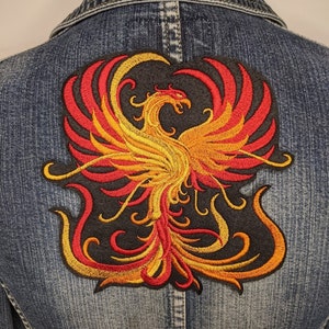 May include: A black denim jacket with a large embroidered patch of a red and yellow phoenix on the back.