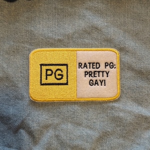 May include: Yellow and white embroidered patch with the text "Rated PG: Pretty Gay!" and a black square with the letters "PG" inside.
