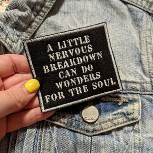 May include: A black and white embroidered patch with the text "A little nervous breakdown can do wonders for the soul".