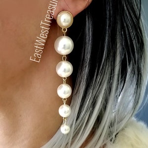 May include: Gold tone drop earrings with a series of white faux pearl beads.