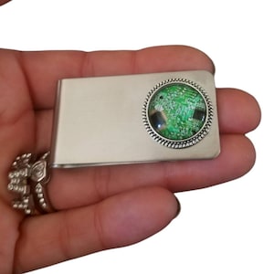 May include: A silver money clip with a round, green, and black, circuit board design in the center.