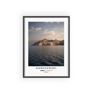 Könnte beinhalten: Gerahmter Druck mit einer malerischen Aussicht auf eine Bergkette über einem Gewässer unter einem bewölkten Himmel. Das Bild enthält die Koordinaten 44° 54' 58.13" N, 14° 48' 12.63" E unten. Der Druck ist in einem schwarzen Rahmen.
