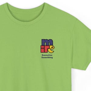 Puede incluir: Camiseta verde lima con un pequeño diseño bordado en el pecho. El diseño presenta las letras "m" e "ir" en azul y rojo, con una cara sonriente amarilla. El texto "Executive Something" está debajo.