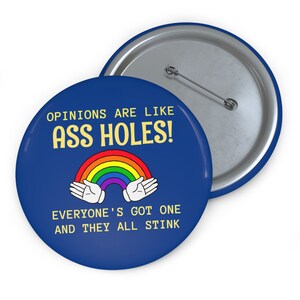 May include: A blue button with the text "OPINIONS ARE LIKE ASS HOLES!" in yellow. A rainbow graphic is centered below the text, with two cartoon hands. The text "EVERYONE'S GOT ONE AND THEY ALL STINK" is below the rainbow.