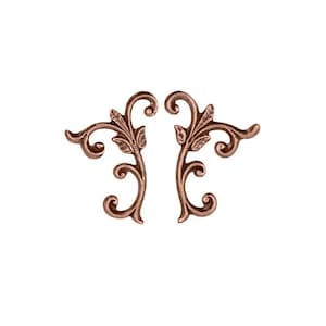 May include: Two ornate copper-colored metal scrollwork embellishments with a floral design. The scrolls are symmetrical and have a delicate, intricate design.