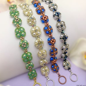 Op de afbeelding: Vier kralenarmbanden met kralen en sluitingen in verschillende kleuren. De armbanden zijn groen, wit, blauw en zilver.