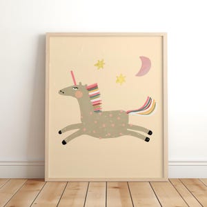 May include: A framed print featuring a whimsical illustration of a running unicorn. The unicorn is gray with pink polka dots, a pink horn, and a rainbow mane and tail. Yellow stars and a pink crescent moon are in the background. The frame is light brown.