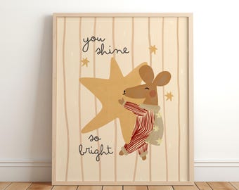 May include: A framed art print featuring a cartoon mouse hugging a large star. The mouse wears red and white striped pajamas and a cape with star accents. The text "you shine so bright" is written on the print.
