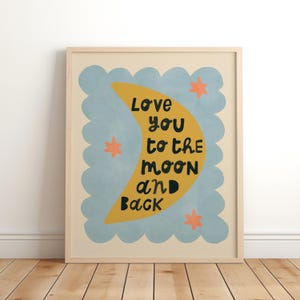 May include: A framed art print with a light wood frame. The artwork features a yellow crescent moon with the words "Love you to the moon and back" in black. The background is a light blue with orange star accents.