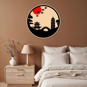 May include: A black and white silhouette wall decor featuring a Japanese-style landscape with a pagoda, bridge, trees, and birds flying over a red sun.