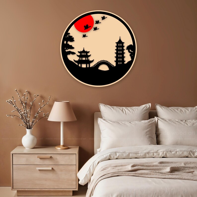 May include: A black and white silhouette wall decor featuring a Japanese-style landscape with a pagoda, bridge, trees, and birds flying over a red sun.