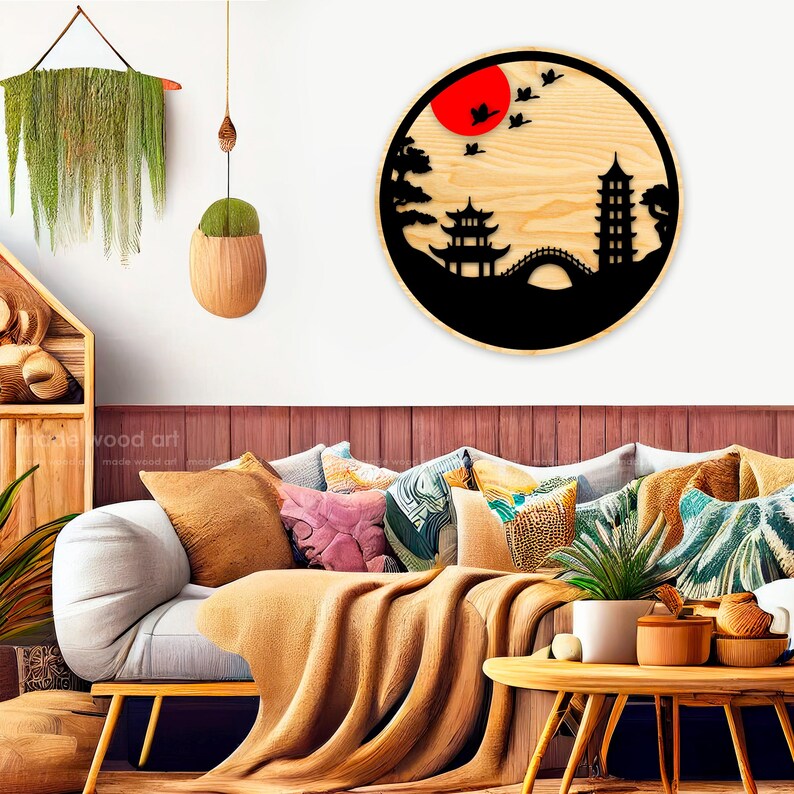 May include: A wooden wall decor featuring a black silhouette of a Japanese pagoda, bridge, and trees against a red sun and a light wood background.