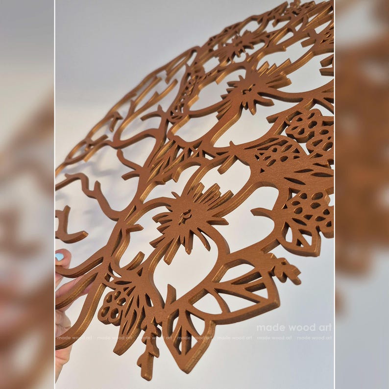 May include: A circular brown wooden wall art piece featuring an intricate laser-cut design of a tree with stylized branches, leaves, and floral elements. The surface has a smooth, matte finish, and the text made wood art is visible in the corner.