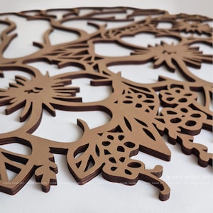 May include: A circular brown wooden wall art piece featuring an intricate laser-cut design of stylized flowers, leaves, and branches. The layered wood construction creates a dimensional effect with cutouts throughout the floral pattern.