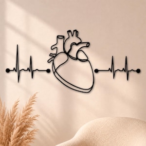 May include: A black metal wall art piece featuring a continuous line drawing of an anatomical human heart centered between two horizontal electrocardiogram heartbeat lines that terminate in solid black circular dots on both ends.